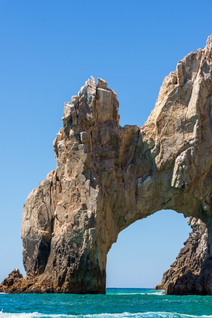 Close-up view of El Arco the iconic natural granite rock arch at Cabo San Lucas rising from turquoise Sea of Cortez water under a clear blue sky in Baja California Sur, Mexico