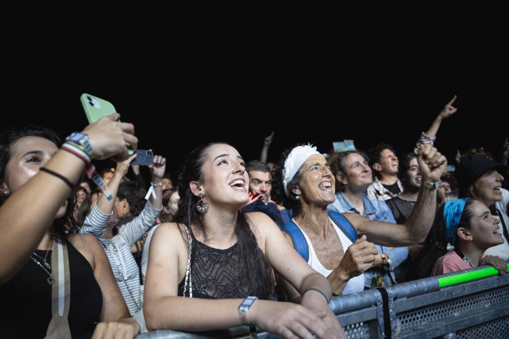 Excited festival crowd cheering and taking photos at a nighttime concert