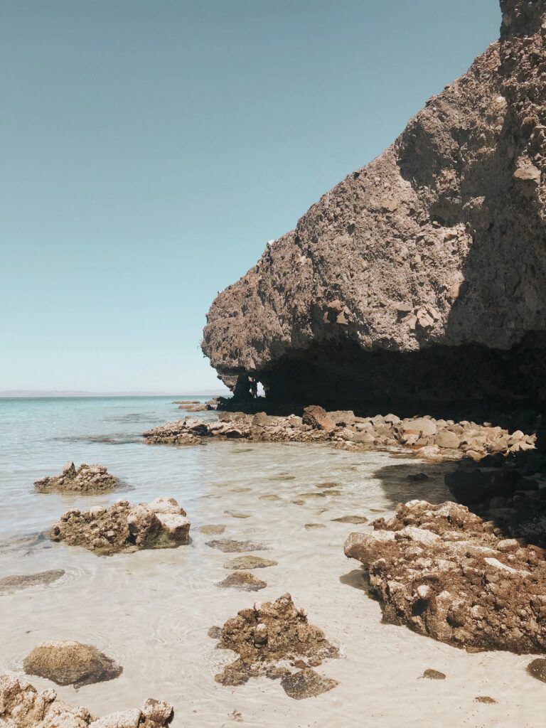 Rocky limestone shore and shallow crystal-clear turquoise lagoon at Playa Balandra beach near La Paz, Baja California Sur, Mexico
