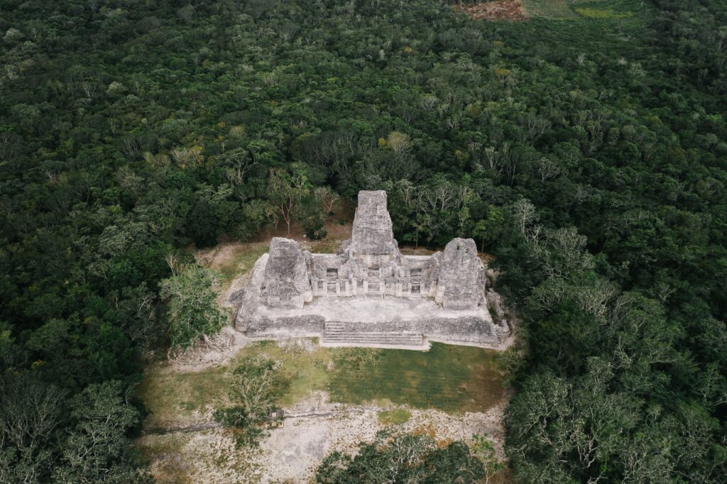 Aerial view of an ancient Maya temple surrounded by dense jungle