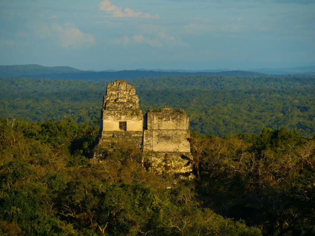 Temple I and Temple II rising above the jungle canopy in late afternoon light at Tikal, Guatemala